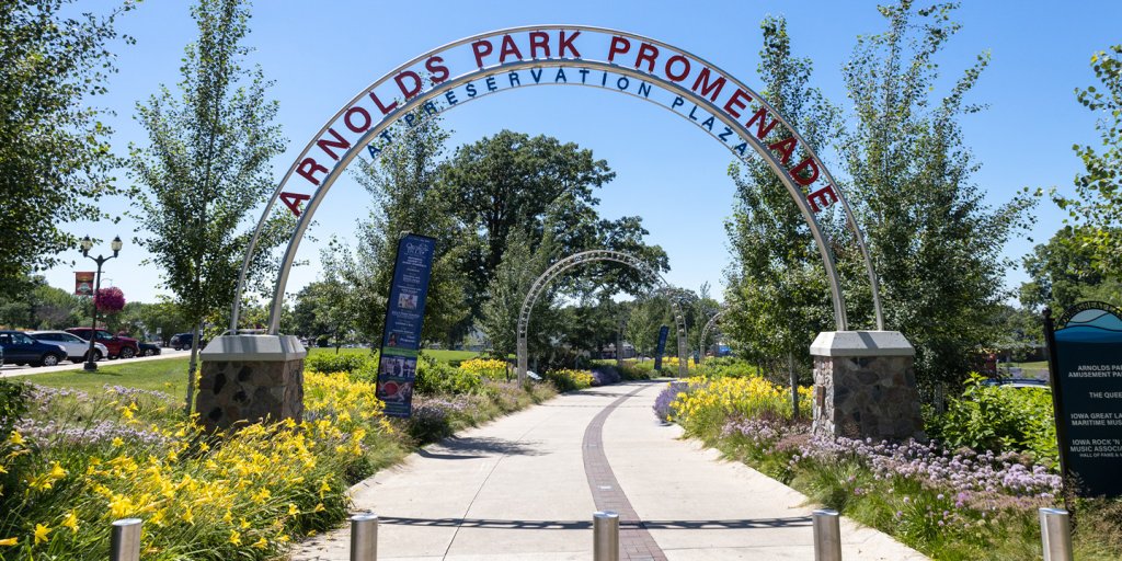 A walkway with a metal arch over it titled Arnolds Park Promenade