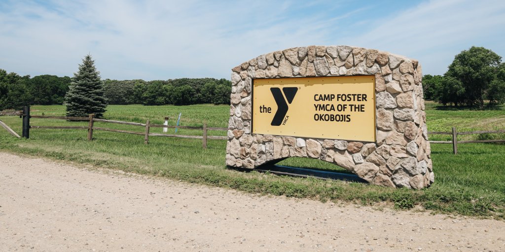 A YMCA camp sign in front of a fence