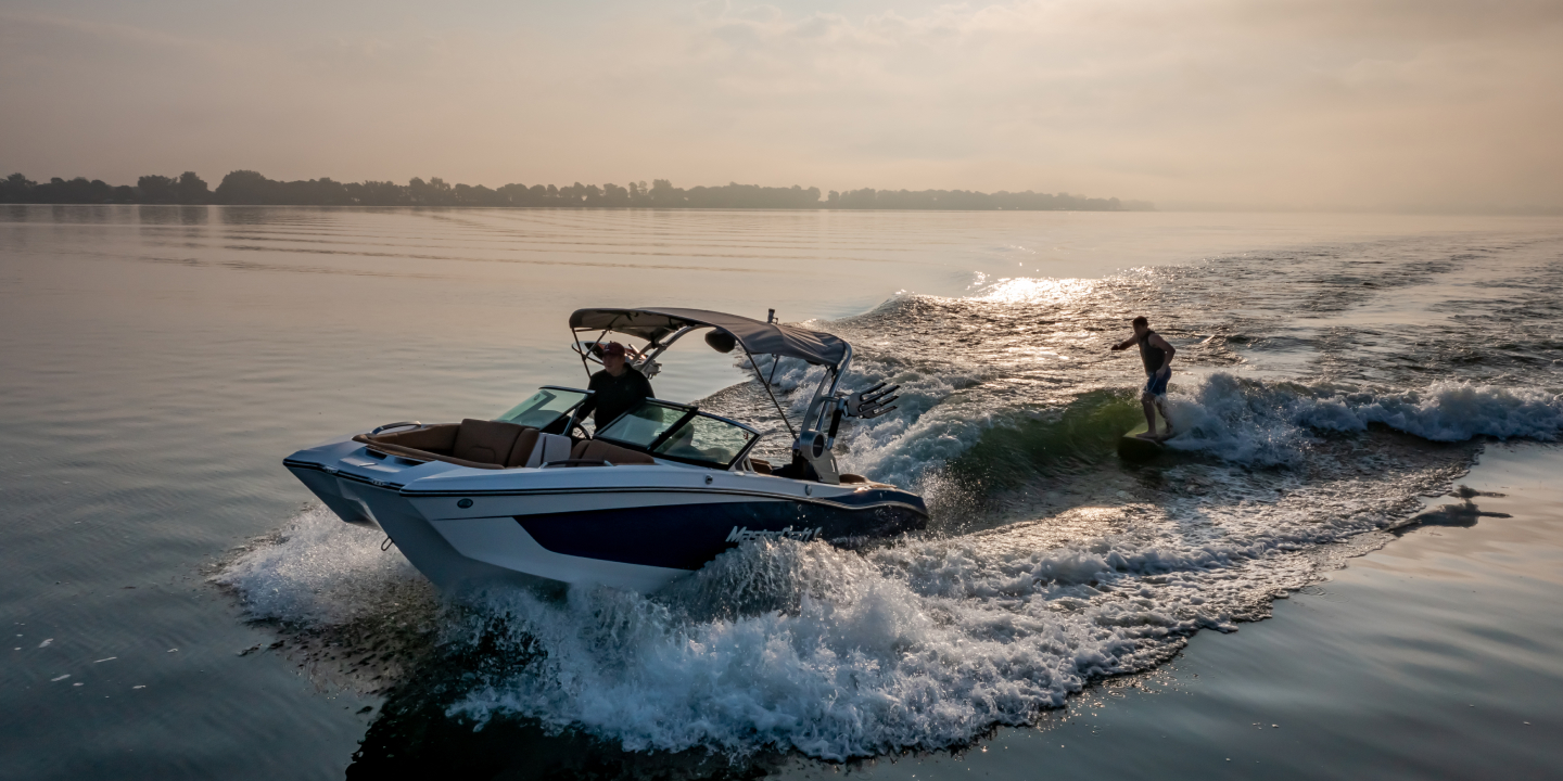 Lakes & Beaches 2 A man drives a boat, towing a man on a wakeboard