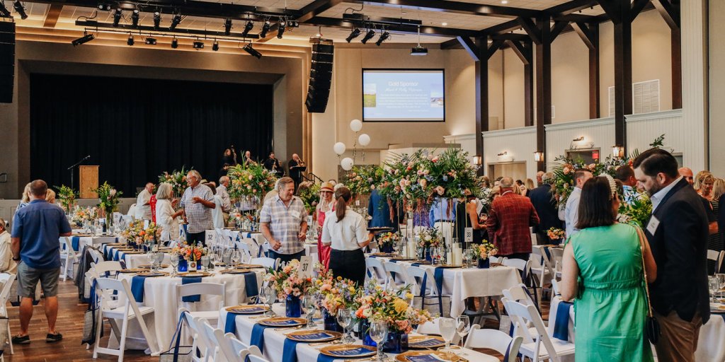Meeting Venues 3 A group of people at an event with blue and white tables and chairs.