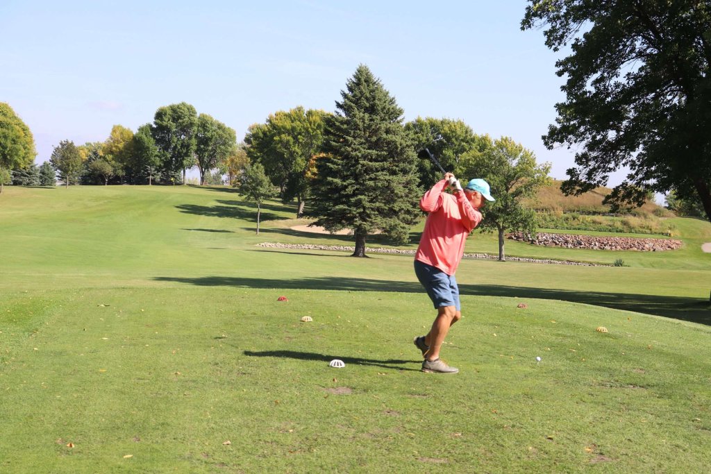 Man taking a swing at a golf ball at Indian Hills Golf Club in Spirit Lake, Iowa
